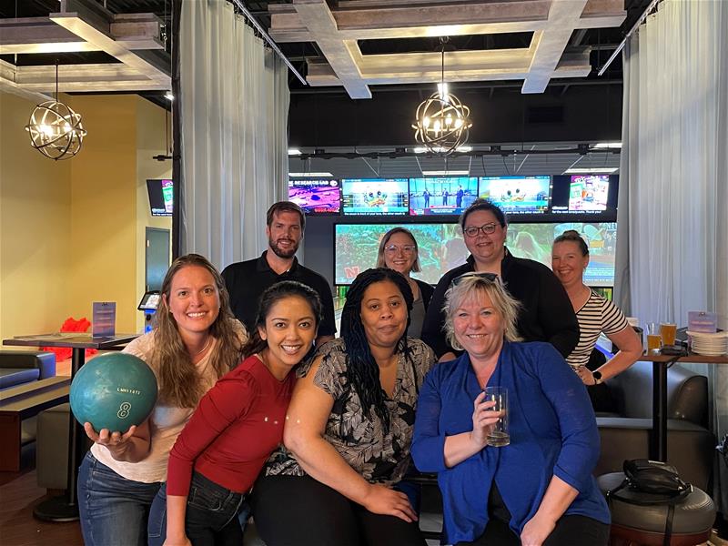 LGRA employees smiling in a group shot at employee bowling event in front in the dining area of the bowling facility