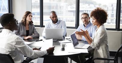 a group of five busines people sitting around a table having a discussion