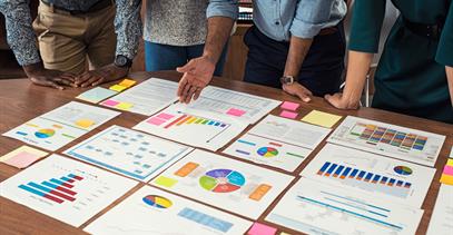 a group of people looking at papers with colorful graphs on a table