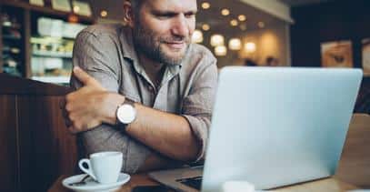 a person sitting at a table with a laptop in a coffee shop