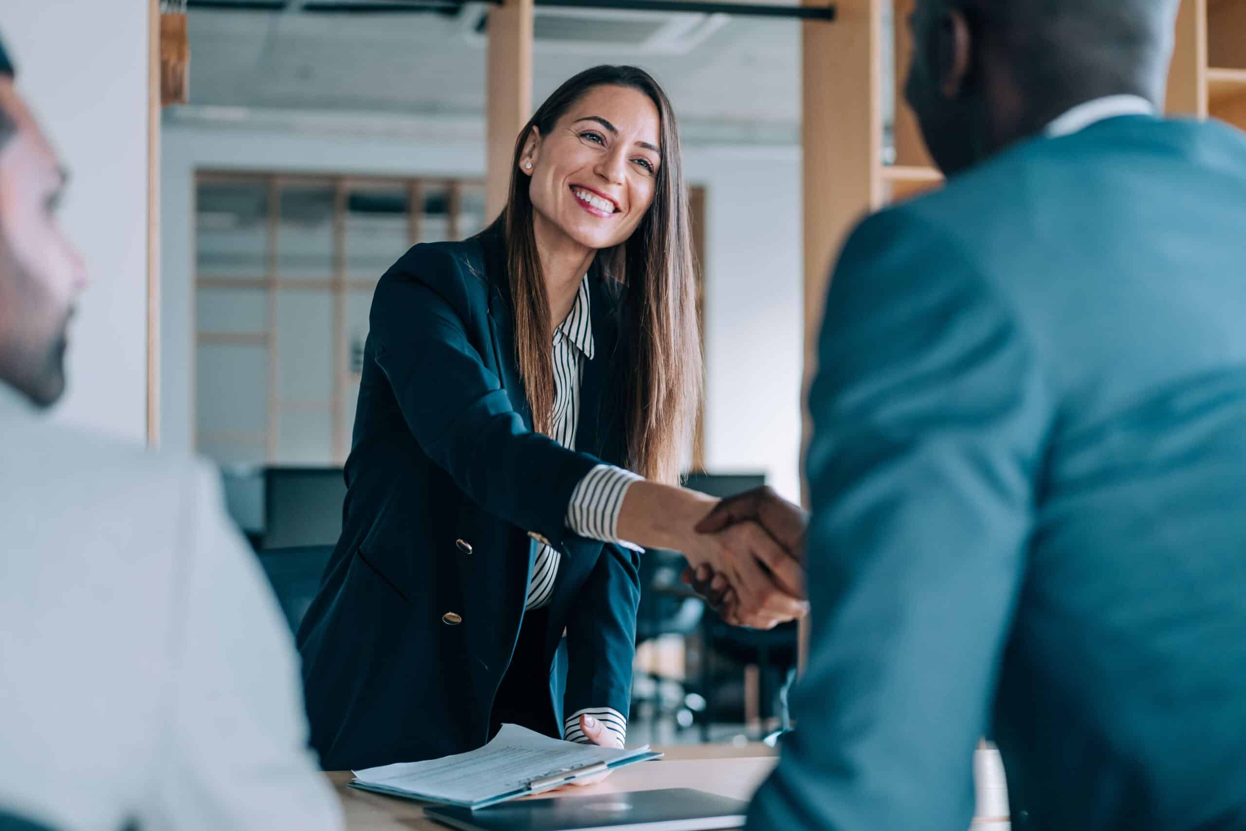 Professional woman smiling while shaking hands with man